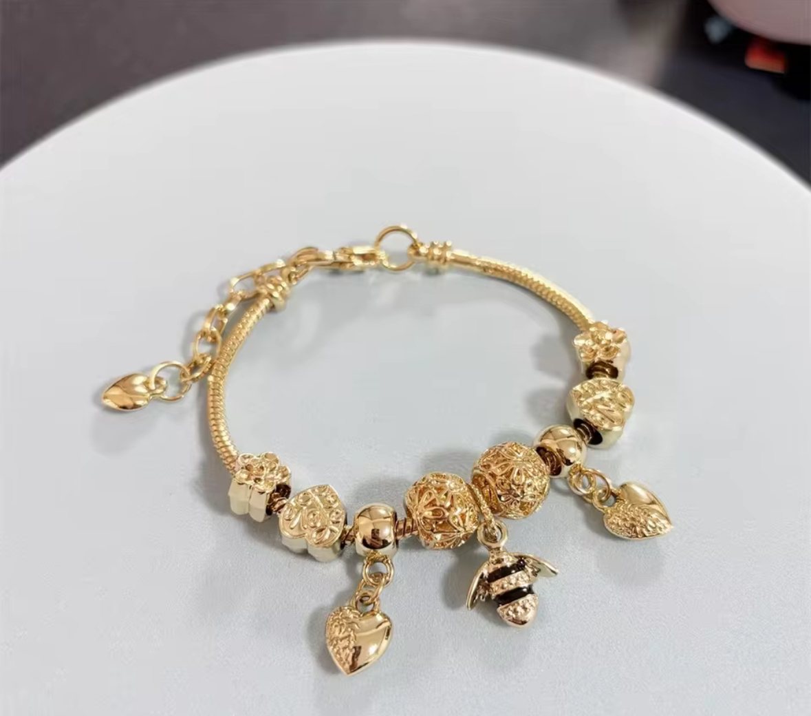 Gold 10 bracelet with a central bee charm and two heart pendants