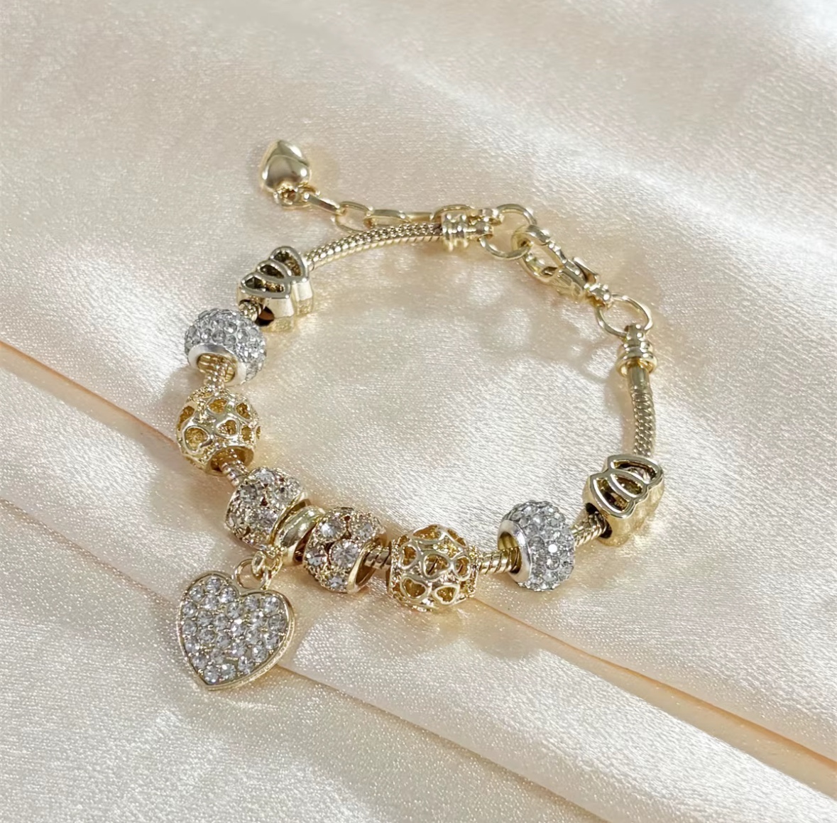 Gold 3 bracelet with a filled rhinestone heart pendant on pale satin