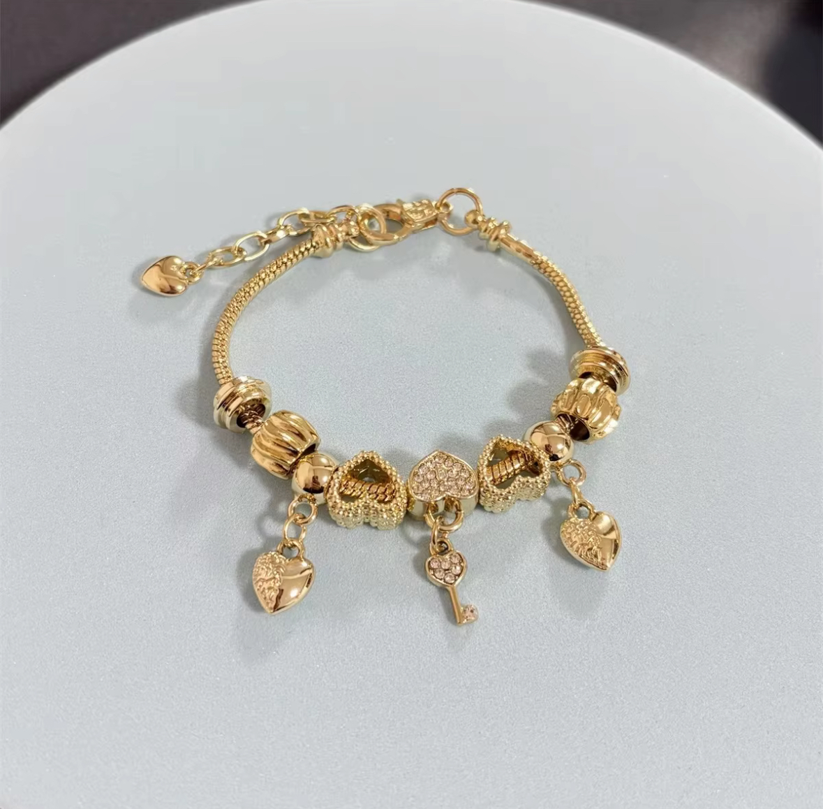 Gold 9 bracelet with two heart pendants and a central heart-shaped key charm